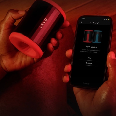 Mężczyzna trzymający czarny LELO F2S i smartfon z aplikacją